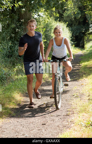 Teenage girl riding a bicycle - adolescents exécutant avec sa partenaire féminine de la bicyclette le long d'un chemin de campagne Anglais Banque D'Images