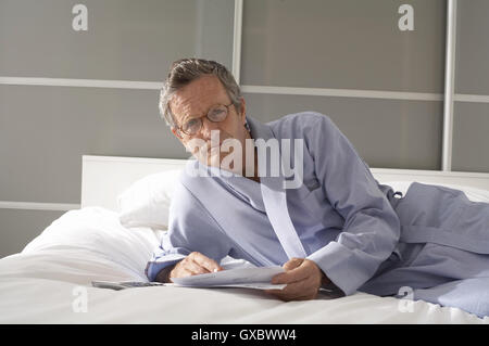 Portrait of senior man reclining on bed vérification Banque D'Images