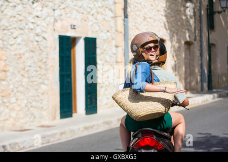 Jeune femme équitation leurs par village à dos, Majorque, Espagne Banque D'Images