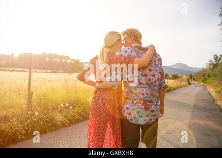 Vue arrière du couple se promener le long de la route en milieu rural au soleil, Majorque, Espagne Banque D'Images