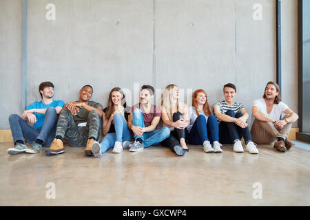 Portrait de groupe d'élèves, garçons et filles assis sur le plancher dans une rangée à l'enseignement supérieur college Banque D'Images