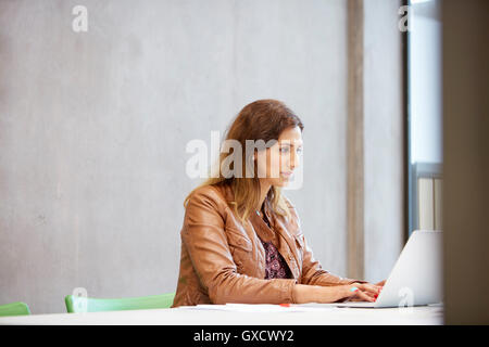 Female designer typing on laptop in design studio Banque D'Images