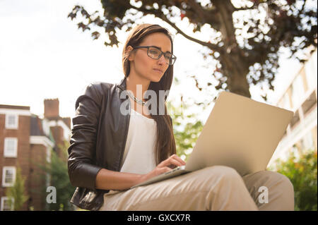 Businesswoman typing on laptop in city, London, UK Banque D'Images