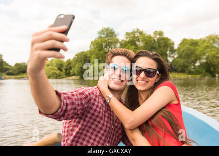 Couple en bateau aviron selfies smartphone dans Regents Park, London, UK Banque D'Images