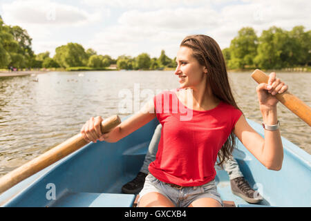 Jeune femme et ami en bateau à rames dans Regents Park, London, UK Banque D'Images