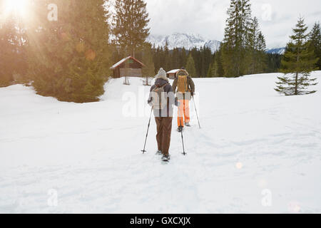 Couple snowshoeing voyage paysage enneigé, vue arrière, Elmau, Bavière, Allemagne Banque D'Images