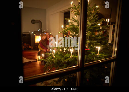 Mère et fils assis à la maison à Noël, à la recherche de l'arbre de Noël illuminé à Banque D'Images