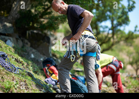 Rock climber on hillside la préparation de matériel d'escalade sur du harnais de sécurité Banque D'Images