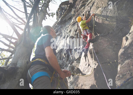 Low angle view of friends climbing rock face Banque D'Images