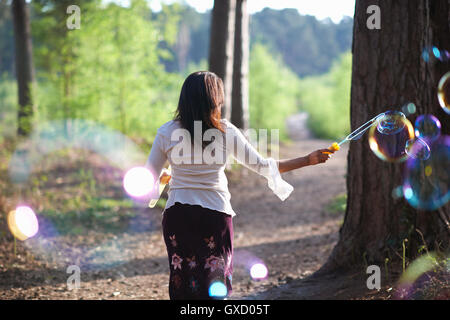 Rear view of woman in forest faire des bulles avec bubble wand Banque D'Images