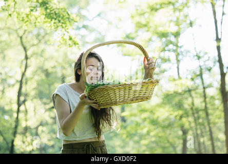 Young woman smelling se nourrissaient d'herbes sauvages en forêt, Noci, Verbania, Piemonte, Italie Banque D'Images