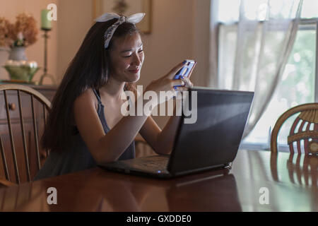 Teenage girl reading textes smartphone dans la salle à manger Banque D'Images