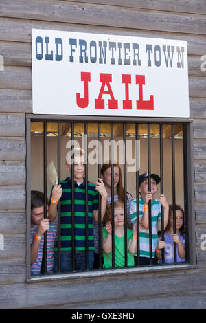 Enfants posent dans l'ancienne ville frontière de prison derrière les barreaux pendant Cheyenne Frontier Days, 22 juillet 2015 à Cheyenne, Wyoming. Frontier Days célèbre les traditions de l'ouest cowboy avec un rodéo, défilé et juste. Banque D'Images