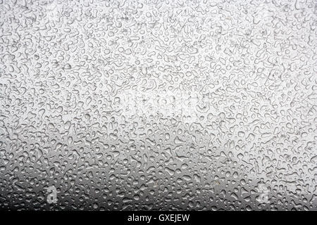 Perles de l'eau congelée après une tempête de neige fondue créer des motifs intéressants sur l'extérieur d'un fini métallique argent automobile. Banque D'Images