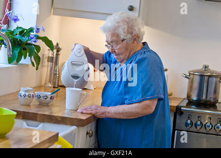 Personnes âgées indépendant 96 ans dame de prendre une tasse de thé dans sa collectivité moderne cuisine maison Banque D'Images