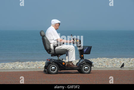 Personnes âgées MAN RIDING SCOOTER HANDICAP SUR LA PROMENADE CÔTIÈRE RE MOBILITÉ TOURISME MEDITERRANEE Les retraités LES PENSIONS DE RETRAITE DE LA MOBILITÉ Banque D'Images