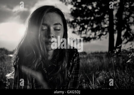 Pensive woman laying in grass field Banque D'Images