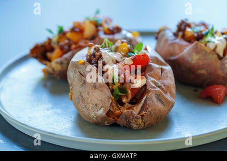 Les patates douces avec les lentilles épicées, le poivron et la tomate, le thym, l'ail fleurs et la crème chipotle Banque D'Images