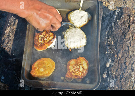 La cuisson des gâteaux sur le feu. Le processus de cuisson la plaque de cuisson avec des crêpes sur le feu de camp. Banque D'Images