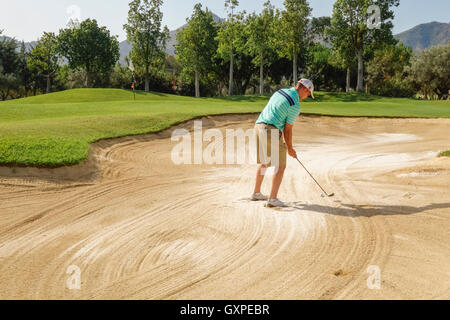 Golfeur frapper la balle de l'intérieur de bunker, Lauro Golf, Malaga, Andalousie, espagne. Banque D'Images