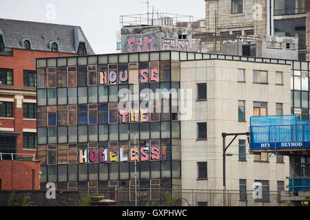 Immeuble de bureaux à l'abandon de l'écriture graffiti Manchester House sans-abri Les sans-abri dans des affiches de fenêtre vandalisme mendiant mendier de l'argent homele Banque D'Images