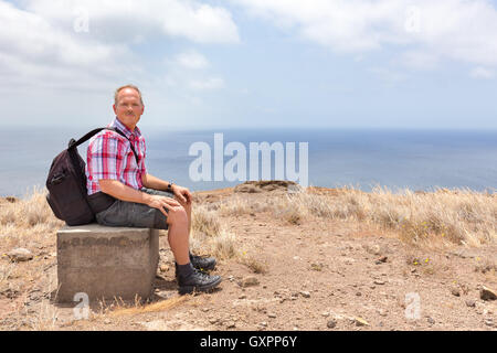 Caucasian man with backpack assis côte à côte sur la mer Banque D'Images