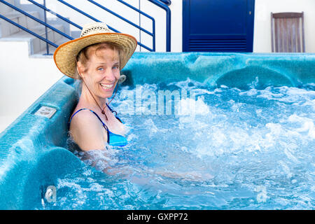 Femme d'âge moyen avec chapeau de paille dans le bain baignoire avec des bulles Banque D'Images