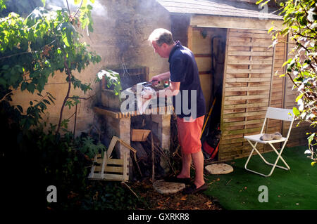 L'homme à la maison dans le jardin avec la côte de boeuf cuisson steak sur un barbecue barbecue Banque D'Images