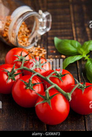 Les tomates fraîches avec le basilic et les épices sur fond de bois grunge jar Banque D'Images