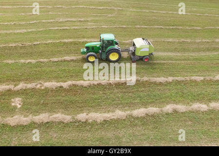 Vue aérienne de tracteur avec le matériel roulant de la ramasseuse-presse à balles de paille sur le champ moissonné Banque D'Images