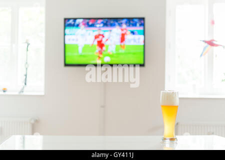 Joueur de football à la télévision et d'un verre de bière de blé sur une table Banque D'Images