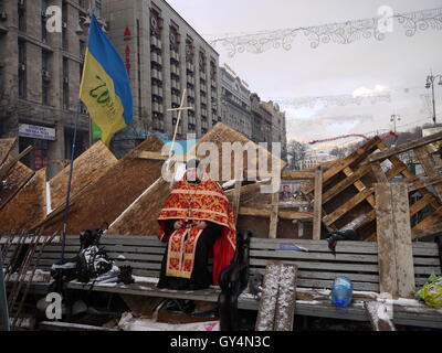 Un prêtre catholique grecque guard une barricade au cours de l'hiver 2013 de protets à Kiev Banque D'Images