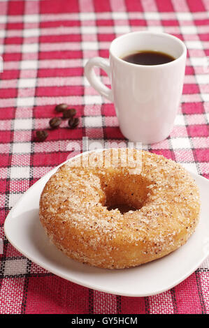 Le petit-déjeuner avec sweet donut et tasse de café noir sur rouge cirée Banque D'Images