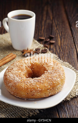 Sweet donut et tasse de café noir sur la table en bois foncé Banque D'Images