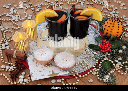 Fête de Noël de l'Alimentation et boisson avec vin chaud, mince pies, pomander orange, d'épices, de bougies, de l'or décorations babiole & Holly. Banque D'Images