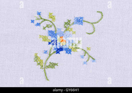 Motif fleur bleu broderie main sur lin blanc. Cross stich multicolores décoration avec fil. L'artisanat. Banque D'Images