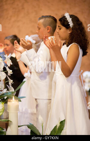 Habillé de façon formelle et hispaniques des enfants de race blanche chanter un hymne au cours de cérémonies de la Première Communion à une Laguna Niguel, CA, l'église catholique. La première Communion est une cérémonie dans certaines traditions chrétiennes au cours de laquelle une personne reçoit d'abord l'Eucharistie. Banque D'Images