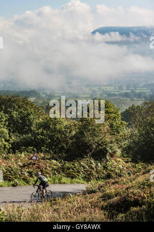 La brume matinale dans la vallée de Ribble, à proximité de Clitheroe Lancashire, North West England, UK. Un cycliste escalade hors de la vallée. Banque D'Images