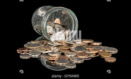 Pot en verre rempli de coins renversé sur une plate-forme Banque D'Images