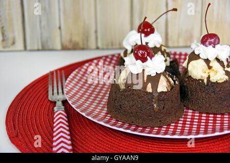 Coupe de glaces avec fudge brownie en sauce rouge et blanc sur plaque de Vichy Banque D'Images