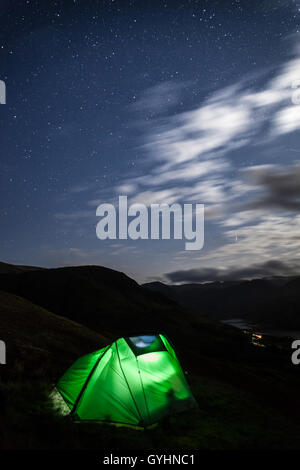Torche lumière rougeoyante de tente de camping sauvage, sous un ciel rempli d'étoiles au-dessus de la lande la lande dans le Lake District Banque D'Images