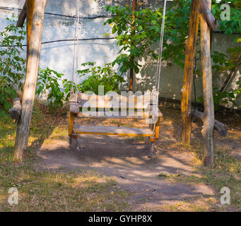 Vintage balançoire en bois banc en cour sur fond de clôture Banque D'Images