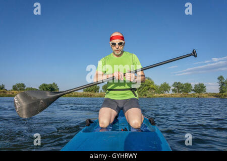 Musclé, senior male pagayeur sur un stand up paddleboard sur un lac dans le Colorado Banque D'Images