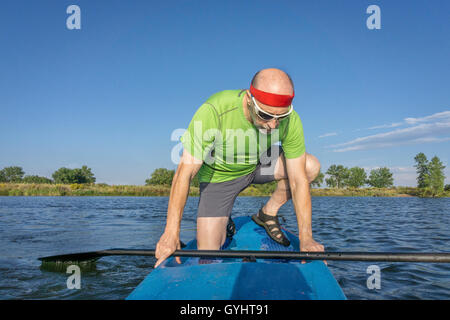 Musclé, senior male pagayeur sur un stand up paddleboard sur un lac dans le Colorado Banque D'Images