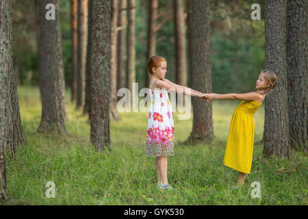 Deux petites filles pour la tenue de mains dans la forêt de pins. Banque D'Images