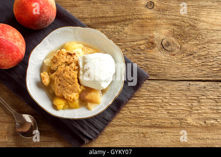 Peach cobbler fait maison avec de la glace à la vanille sur fond de bois rustique avec copie espace - dessert pâtisserie saine Banque D'Images