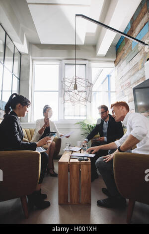 Groupe de personnes créatives assis ensemble et discuter de nouveau projet d'entreprise dans le bureau. Banque D'Images