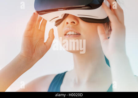 Close up shot of asian woman en utilisant le casque de réalité virtuelle et à la voiture. Femme portant des lunettes VR contre gray backgrou Banque D'Images