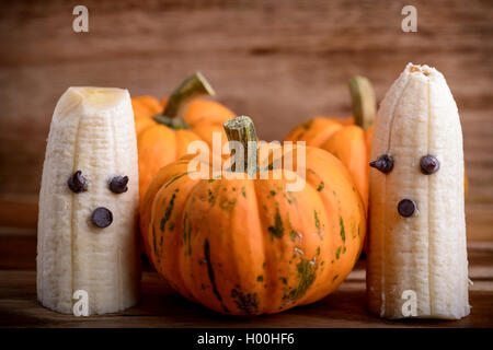 Trois citrouilles et fantômes faits avec banane et chocolat pour l'halloween sur du bois Banque D'Images