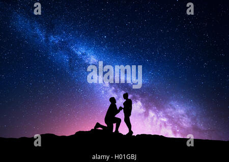 Voie lactée. Paysage de nuit avec des silhouettes d'un homme faire de demande en mariage à sa petite amie et ciel étoilé. Silhouette de lo Banque D'Images